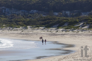 Two couples walk on a beach. Fingal Bay. Port Stephens. Australia.