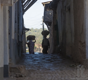 HARAR, ETHIOPIA - DECEMBER 23, 2013: Unidentified women carry things on their heads in narrow alleyways of ancient city of Jugol.