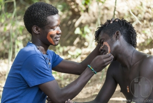 Hamar men paint each other's face in a preparation to a bull jumping ceremony.