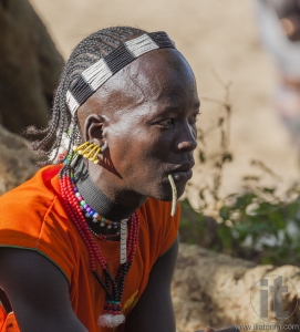Traditionally dressed Hamar man with chewing stick in his mouth.