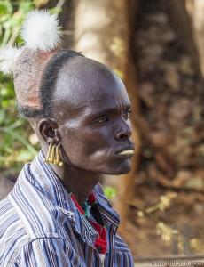 Traditionally dressed Hamar man with chewing stick in his mouth.