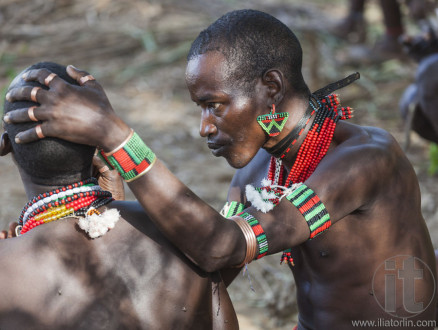 Hamar men paint each other's face in a preparation to a bull jumping ceremony.