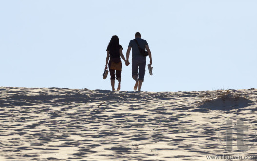 Young couple walks on sand dune. Fingal Bay. Port Stephens. Australia.