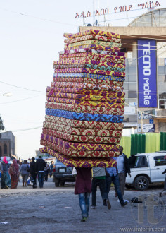 ADDIS ABABA. ETHIOPIA - DECEMBER 21, 2013 Man carries pile of foam mattresses in Merkato market. Merkato market is the largest open air market in Africa.