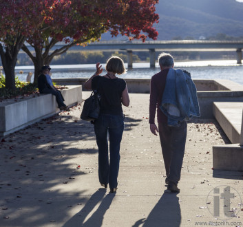Autumn. Couple walks along embankment of Burley Griffin Lake near National Gallery. Canberra. Australia