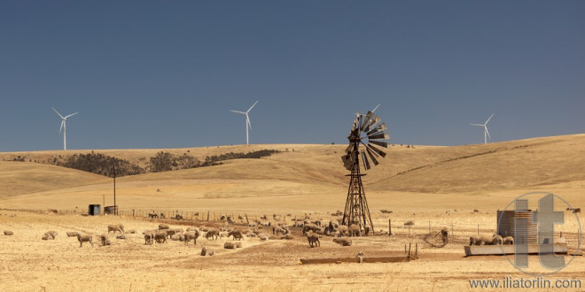 Old broken wind pump and new wind generators distorted by hot air. South Australia.