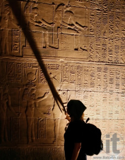 Woman touching the wall with Egyptian Hieroglyphs in Philae Temple near Aswan.