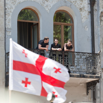 Young men watch military parade from balcony. Tbilisi, Georgia.