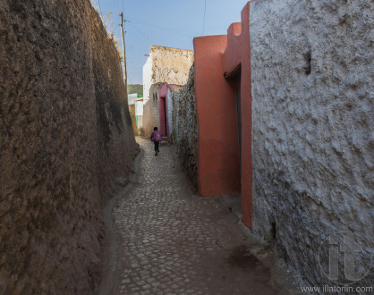 HARAR. ETHIOPIA - DECEMBER 23, 2013: Young boy running as he is late for school in narrow alleyway of ancient city of Jugol.