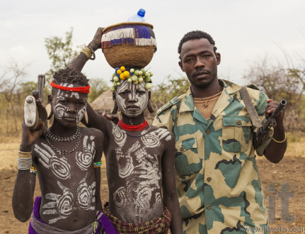Boys from Mursi tribe and a solder with machine guns in Mirobey